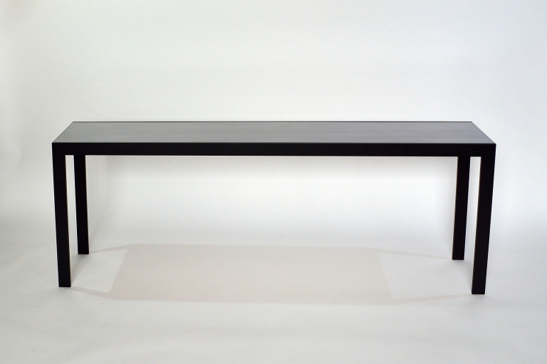 De Gian met een hoogglans of zijdeglans met kunsthars afgewerkt tafelblad als eye-catcher, centraal gezet door get contrast met het minimalistische stalen frame. Toegepast als salontafel, eettafel of console.